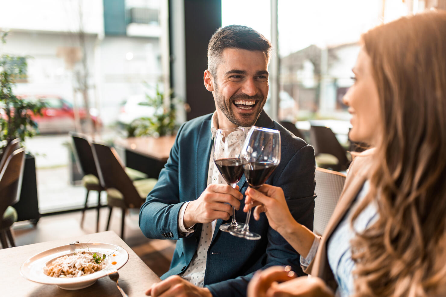 Happy couple eating lunch together in a restaurant and toasting with wine.