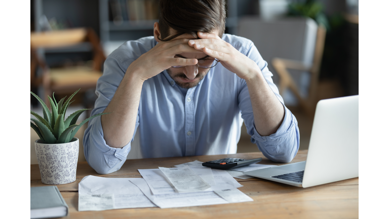 Sad depressed man checking bills, anxiety about debt or bankruptcy