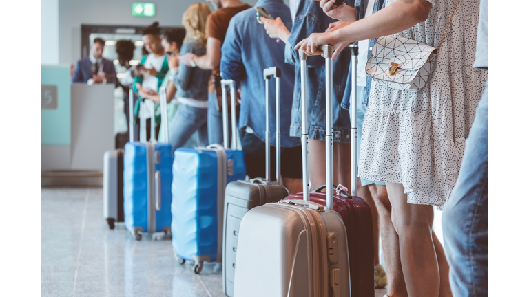 Passengers with luggage waiting in line at airport