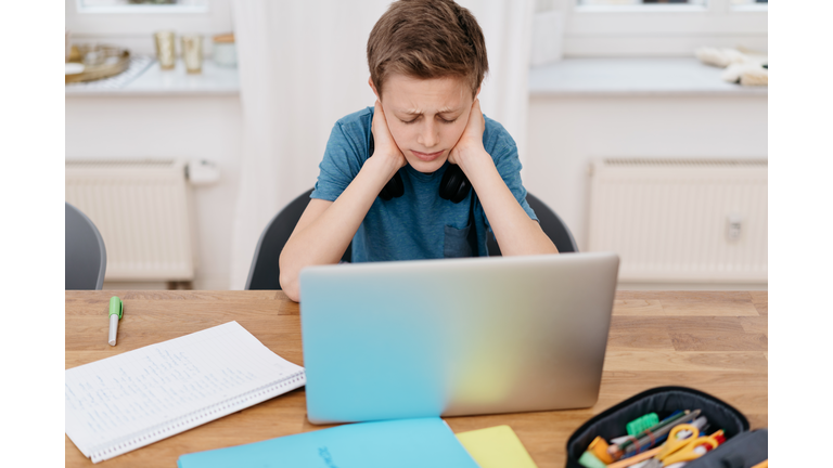 Bored teenager boy sitting at computer