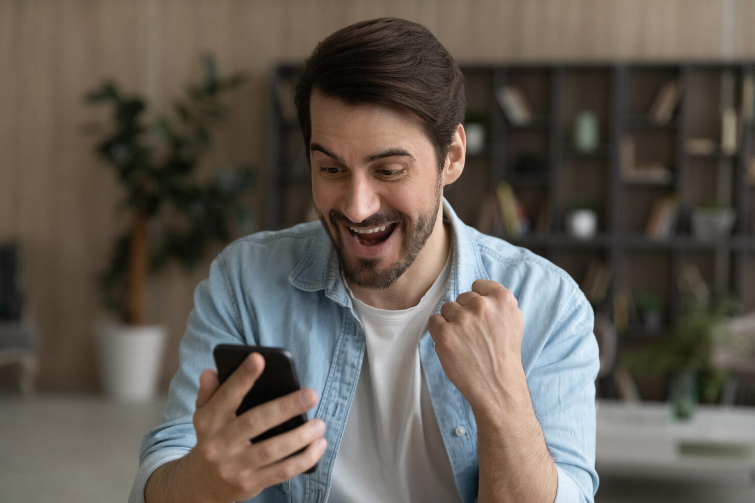 Euphoric bearded male look at cell screen receive online present