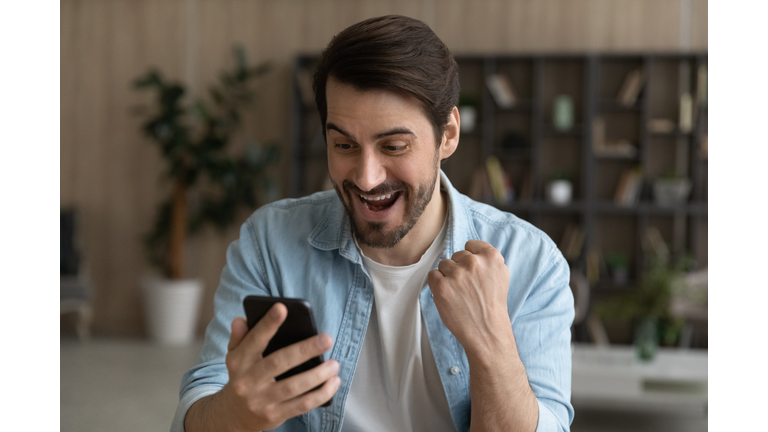 Euphoric bearded male look at cell screen receive online present