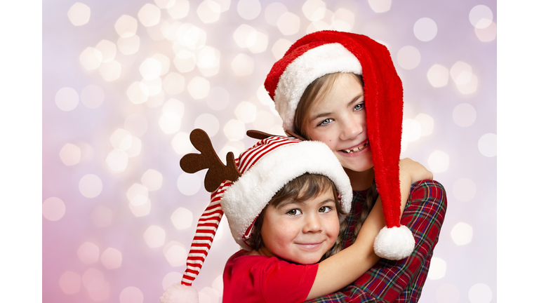 Two children in Christmas hats on a purple background