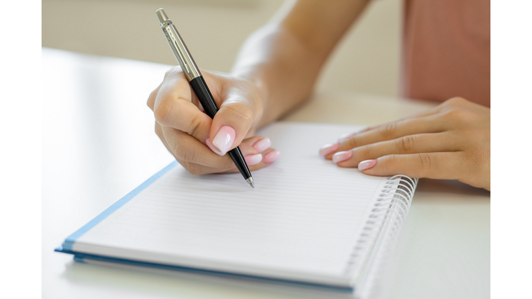 Hands writing notes on notebook