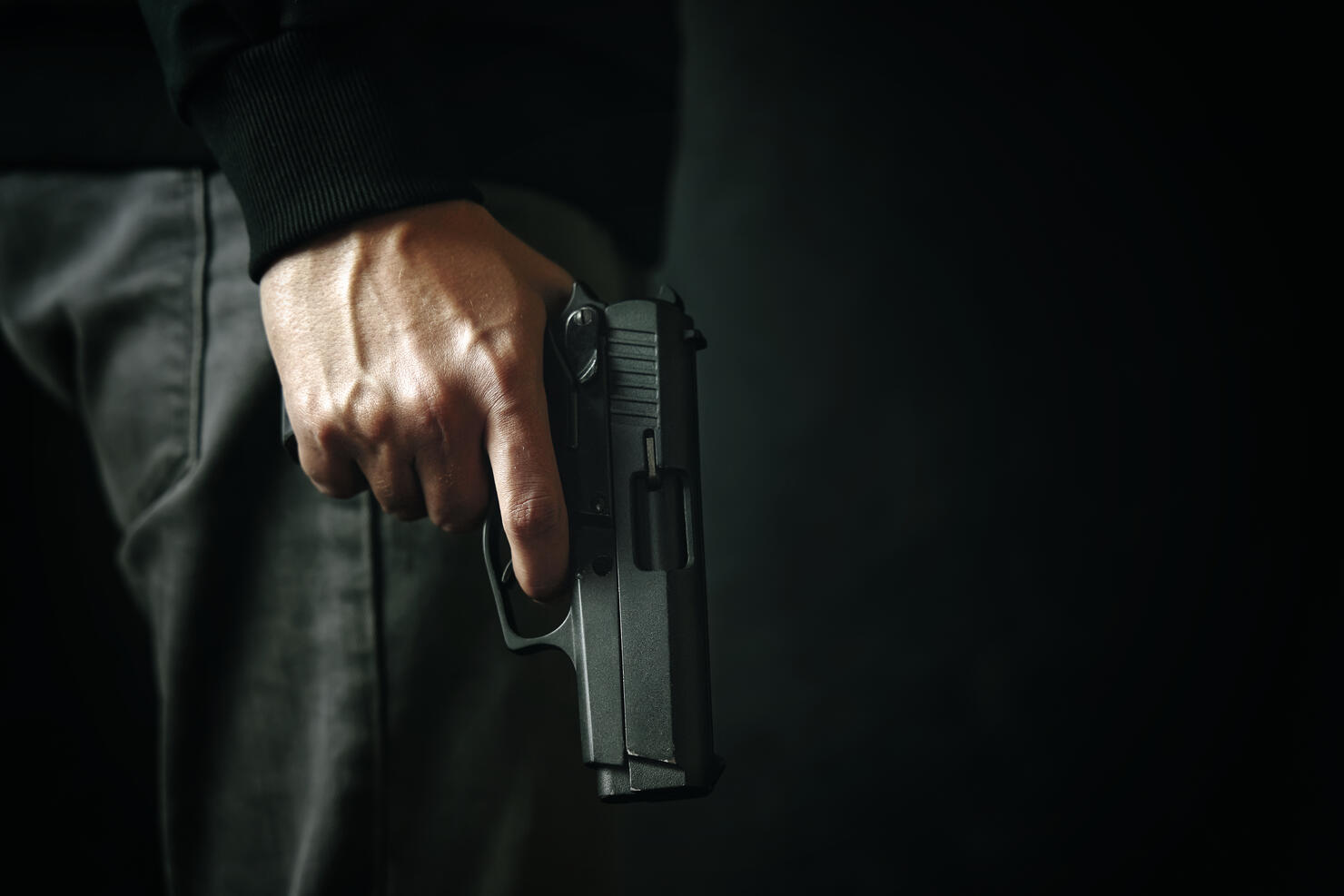 Criminal with revolver on dark background.