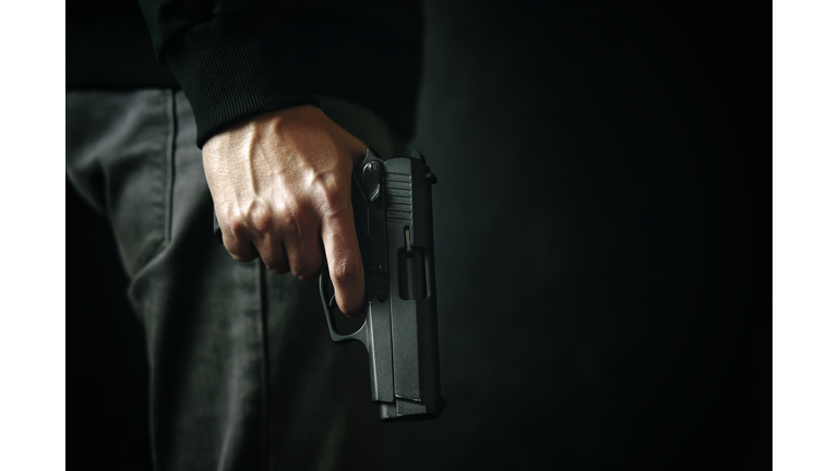 Criminal with revolver on dark background.