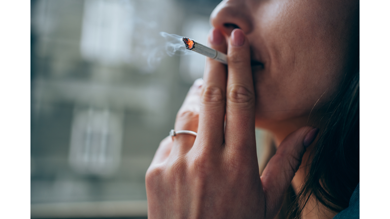 Young woman smoking a cigarette outdoors.