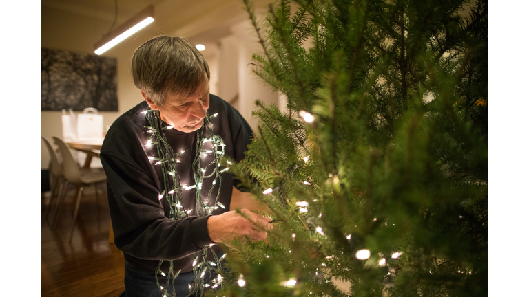 Elderly man works diligently, lighting the Christmas Tree