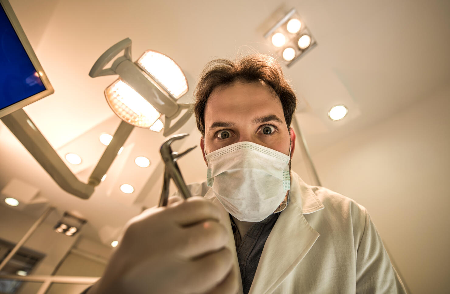 Low angle view of spooky male dentist with pliers.