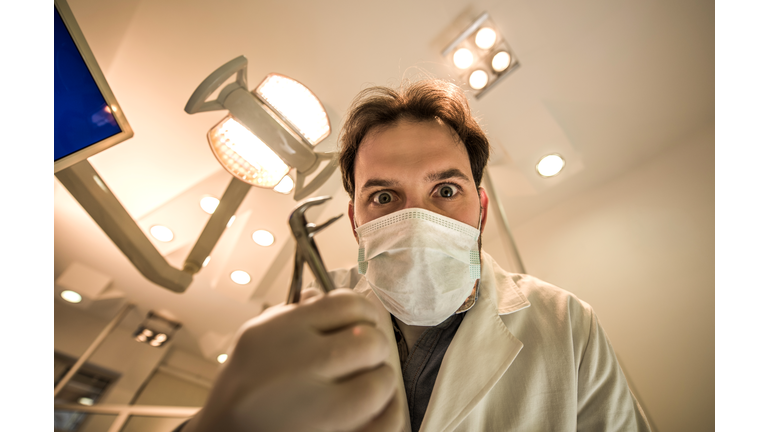 Low angle view of spooky male dentist with pliers.