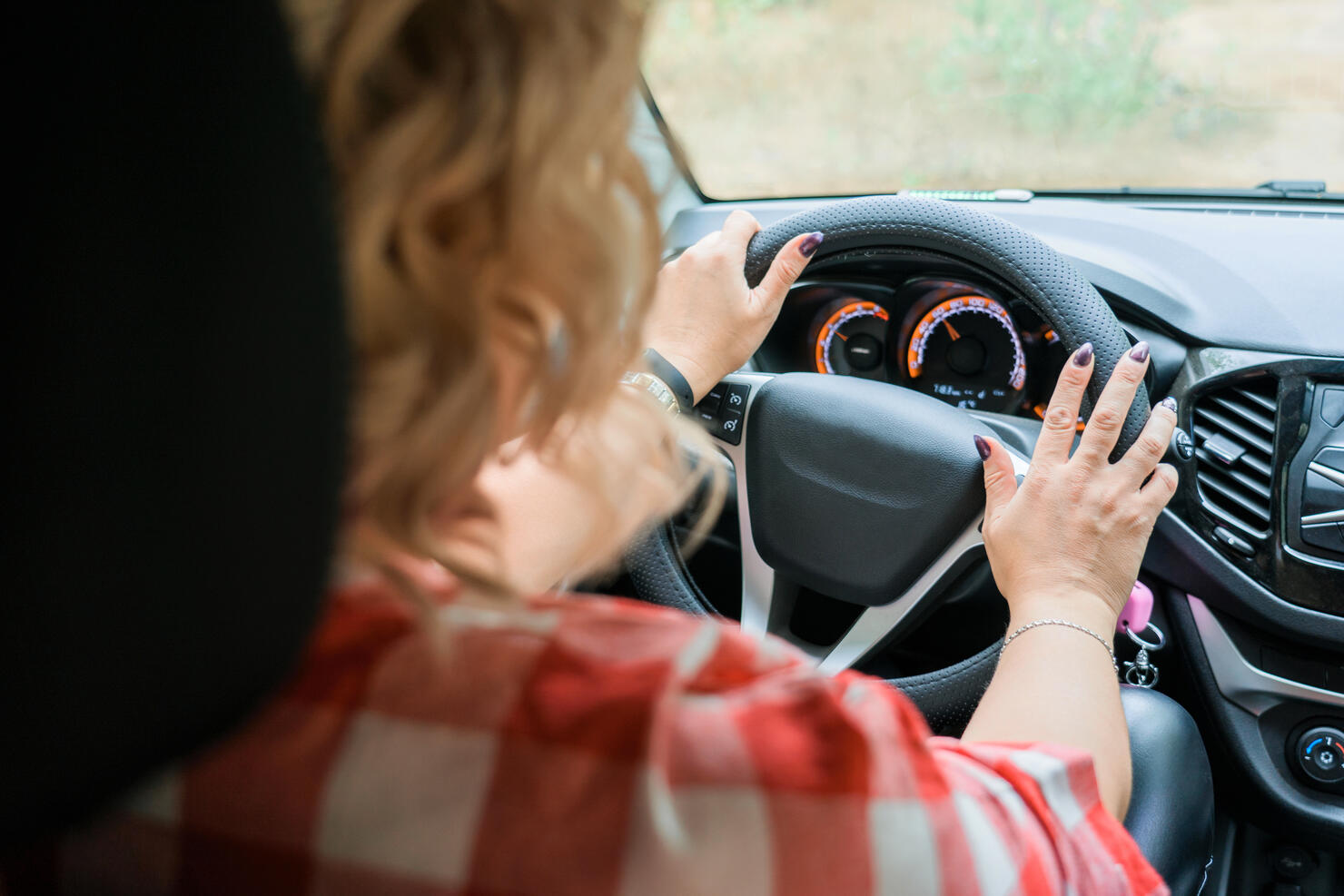 Adult blonde woman driving a car, inside view
