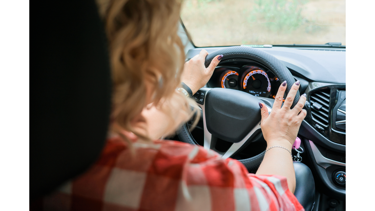 Adult blonde woman driving a car, inside view