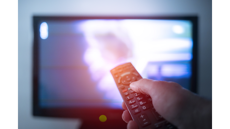 Hand with remote control in front of the tv