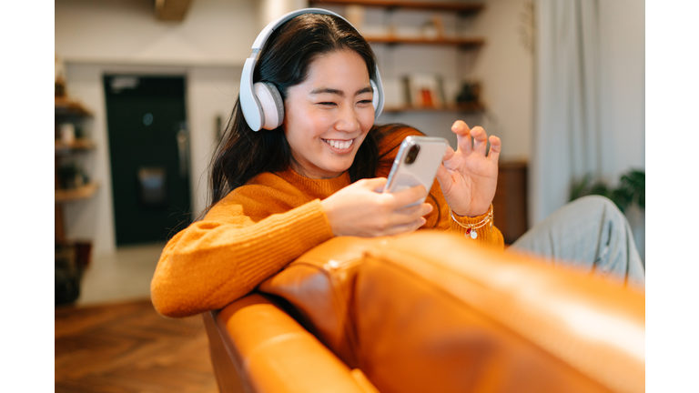 Stylish young woman listening to music at home