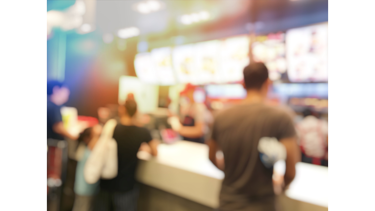 blurred image of people or customer waiting and queuing for order some food and make payment in Fastfood Store at cashier. vintage tone and light effect.