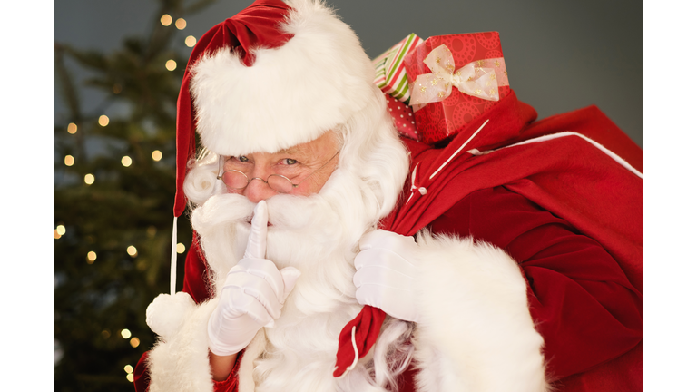 Portrait of Santa Claus with finger on lips, carrying sack over shoulder