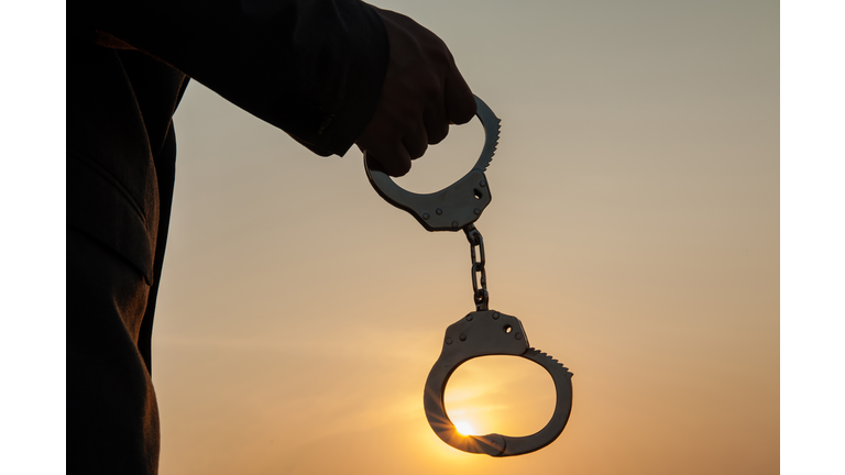 Business Man holding handcuffs after releasing over sunset background