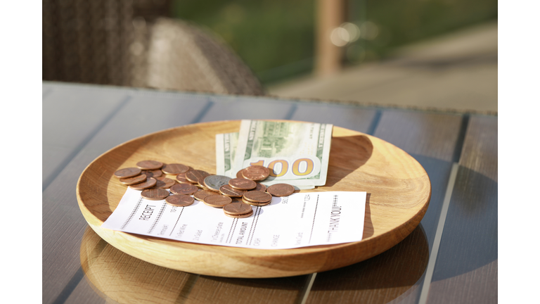 Wooden plate with payment for order and receipt on table, closeup. Leave tip