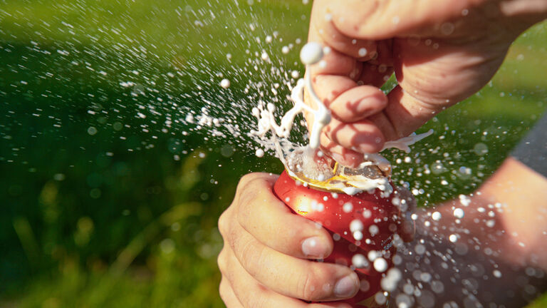 CLOSE UP: Unrecognizable thirsty man opens a can of shaken up beer during picnic