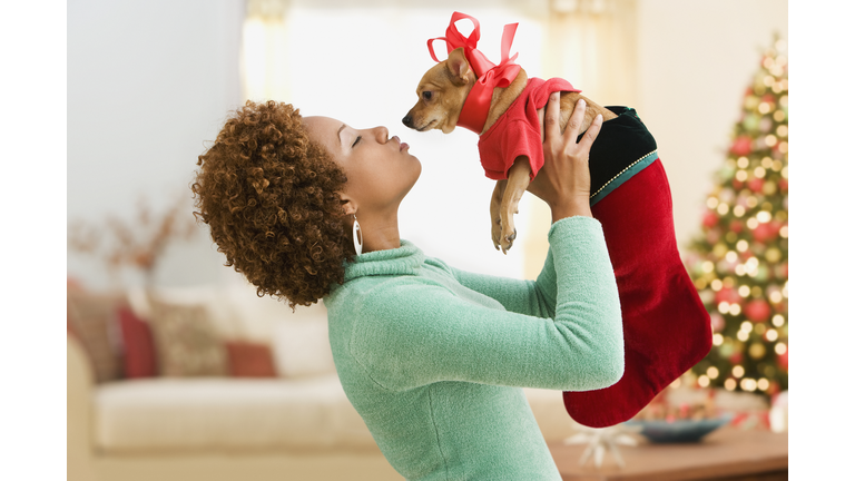 Hispanic woman kissing pet dog in costume