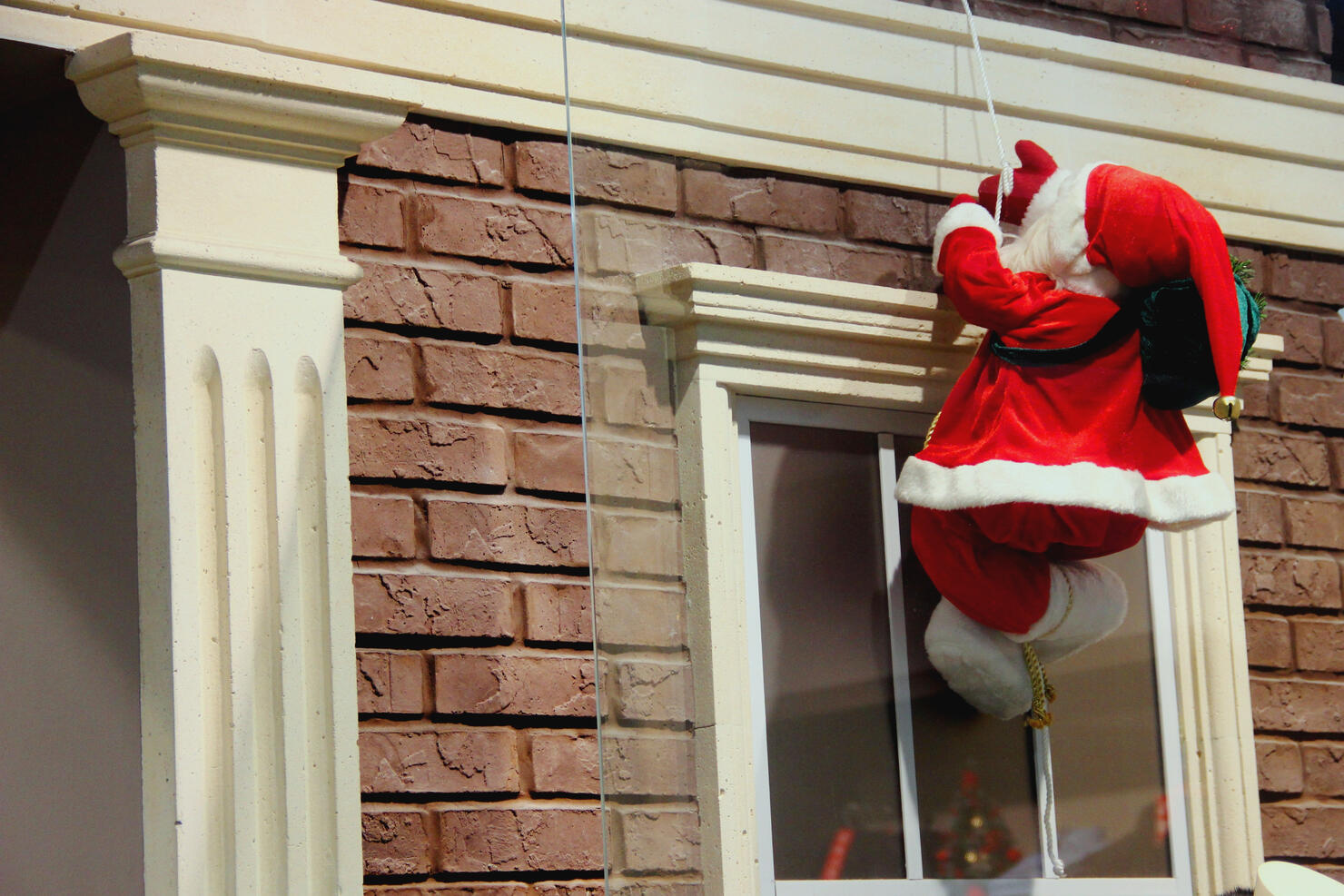 Santa Claus descends on a rope. Christmas decoration of the facade of the building