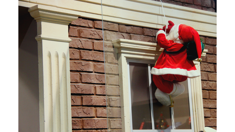 Santa Claus descends on a rope. Christmas decoration of the facade of the building