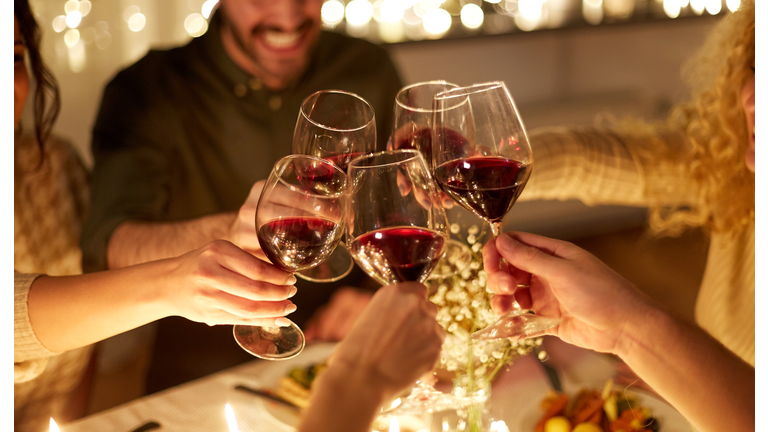 happy friends drinking red wine at christmas party