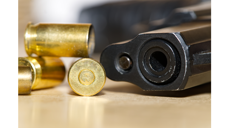 shell casings and barrel of a pistol close-up on a wooden table in a shooting range or at a crime scene. crime concept