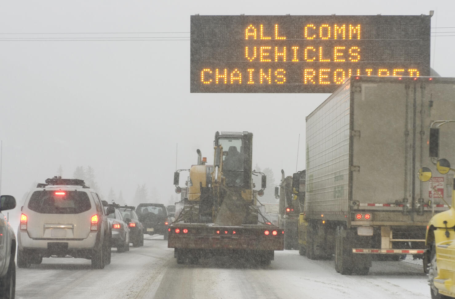 Truck traffic on I-70 highway with blizzard snow chains required