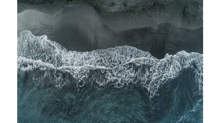 Drone shot looking down on breaking ocean waves and a black sand beach, Tenerife, Spain