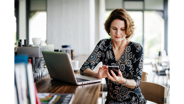 Businesswoman Using Smartphone While Sitting At Restaurant Bar