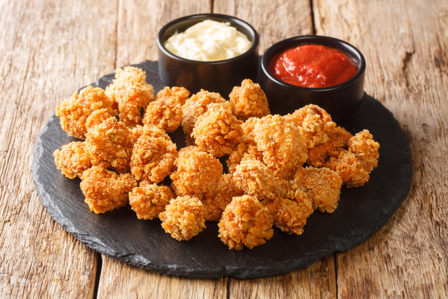 Chicken Popcorn are small slices of chicken that were coated breading and deep fried closeup on the table. Horizontal