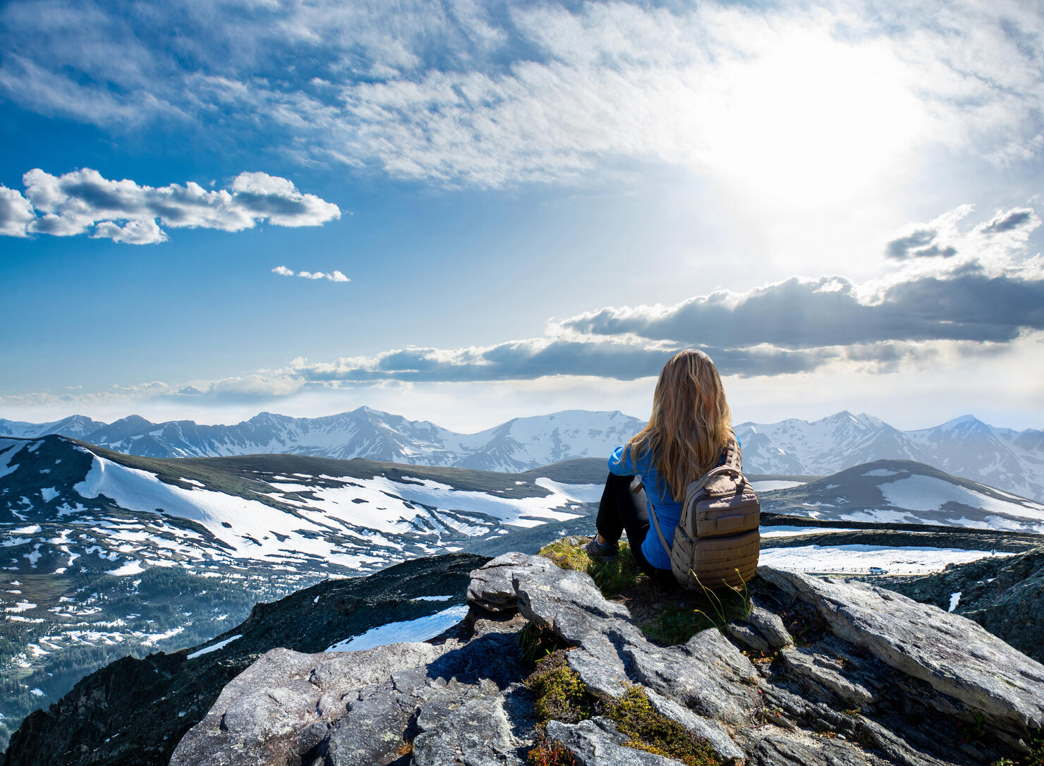 Girl hiker sitting  on top of the mountain looking at beautiful view.