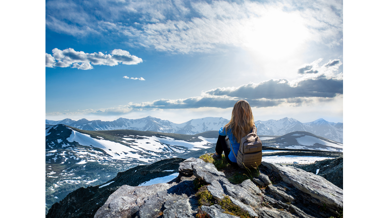 Girl hiker sitting  on top of the mountain looking at beautiful view.