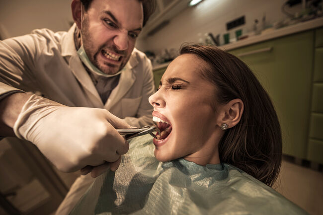 Aggressive dentist about to take out woman's tooth.