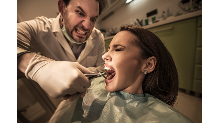 Aggressive dentist about to take out woman's tooth.