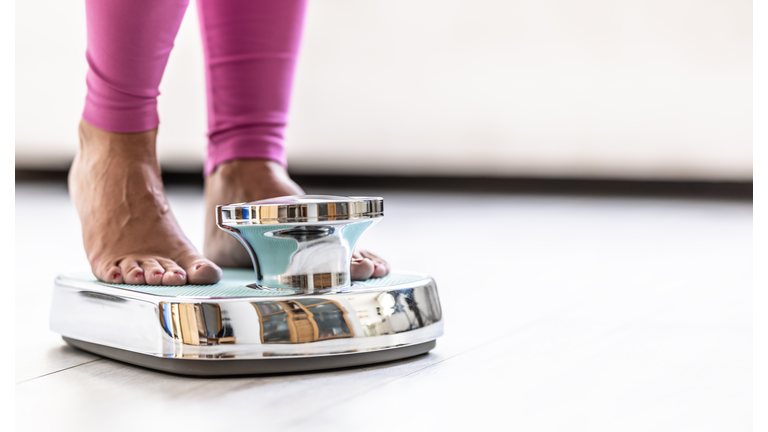 Woman standing on scale; close-up of legs.