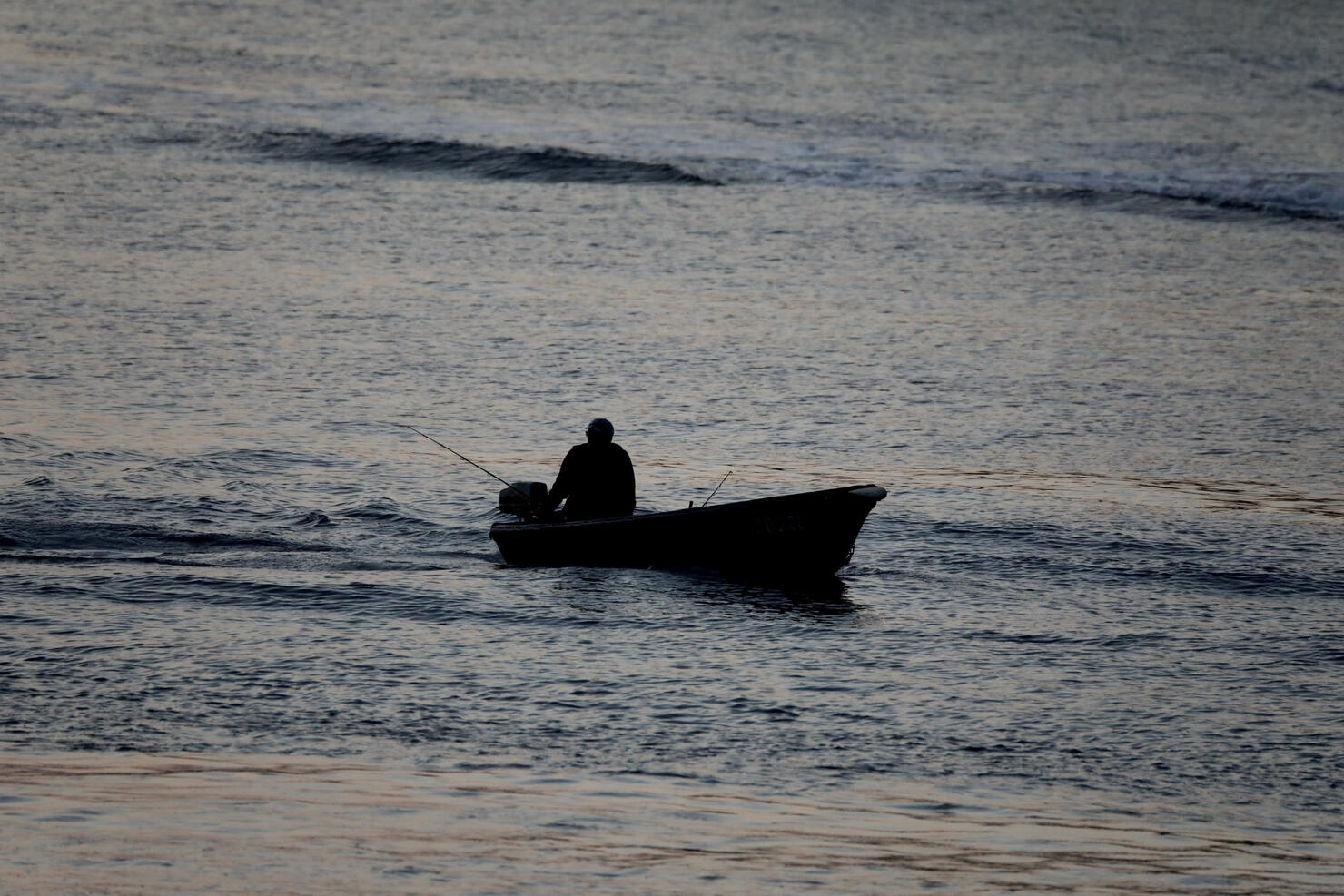 Silhouette of a fisherman in a small motorboat