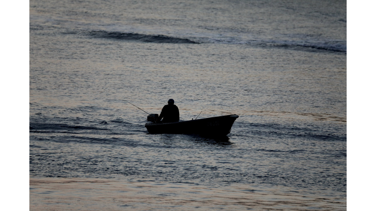 Silhouette of a fisherman in a small motorboat