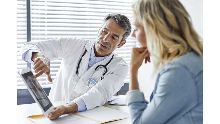 Doctor showing digital tablet to woman in hospital