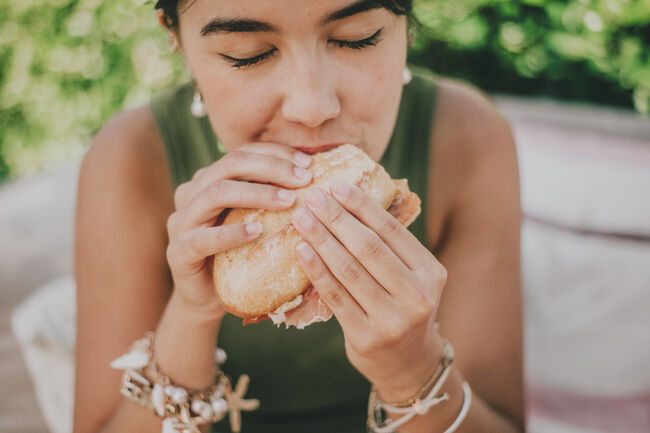 young woman enjoys a serrano ham  sandwich outdoors