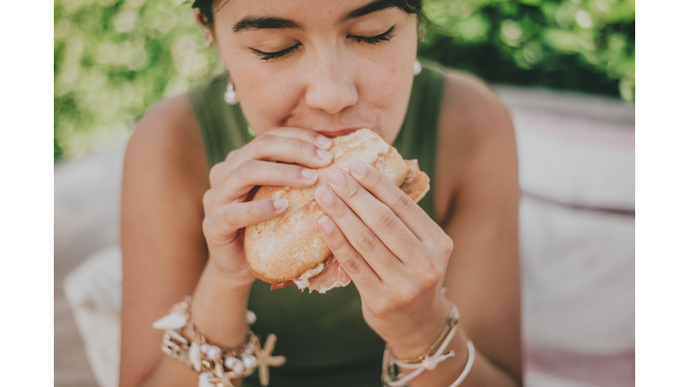 young woman enjoys a serrano ham  sandwich outdoors