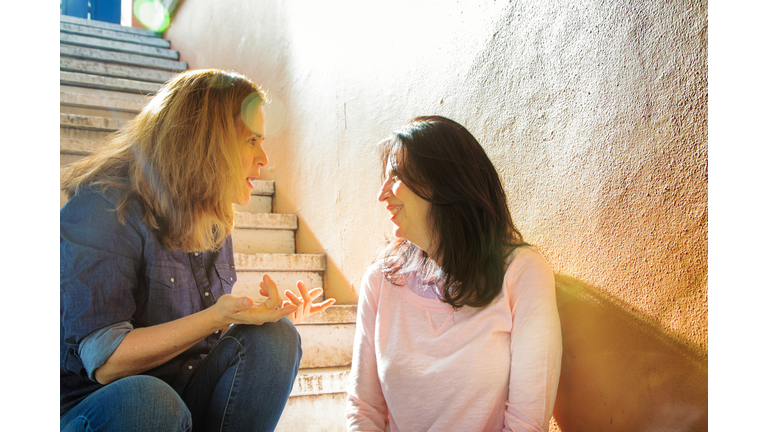 Mature female gossiping with her neighbor in stairway