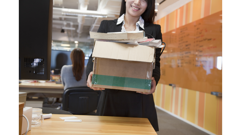 Chinese businesswoman carrying box in office