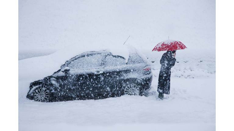 woman on mobile alongside car in a snow drift