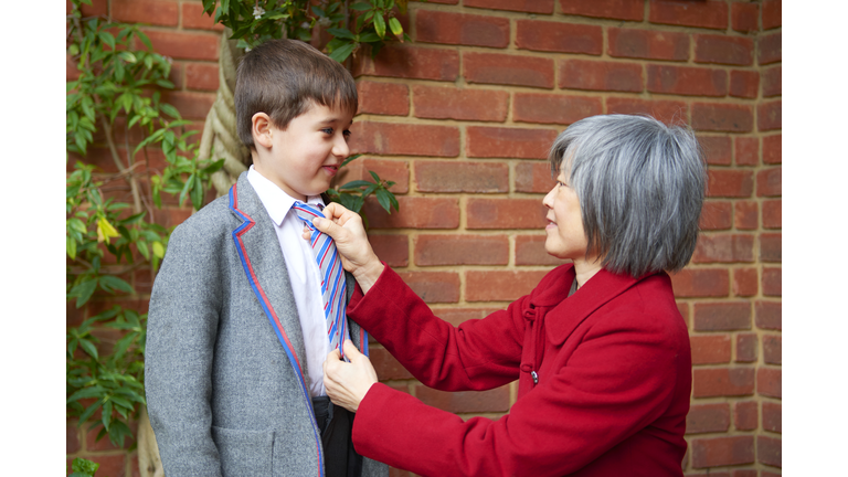 Tiger mother doing up schoolboy son's tie