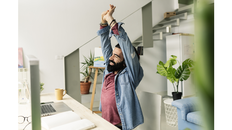 tired man stretches after working with computer