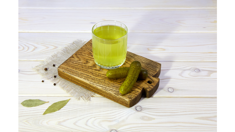 Pickle juice or cucumber pickle on a wooden background. Healthy energy drink for athletes.