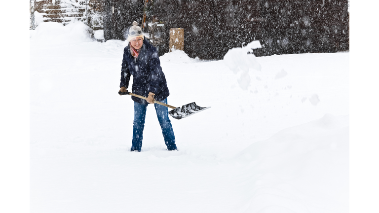 Smiling woman shoveling snow