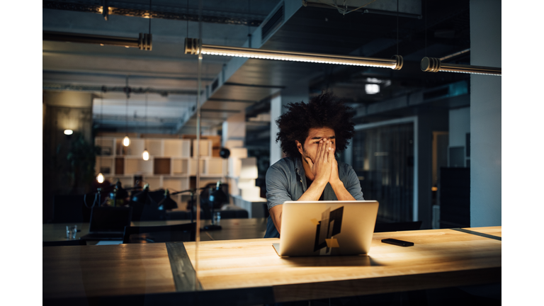 Tired businessman working on laptop at desk